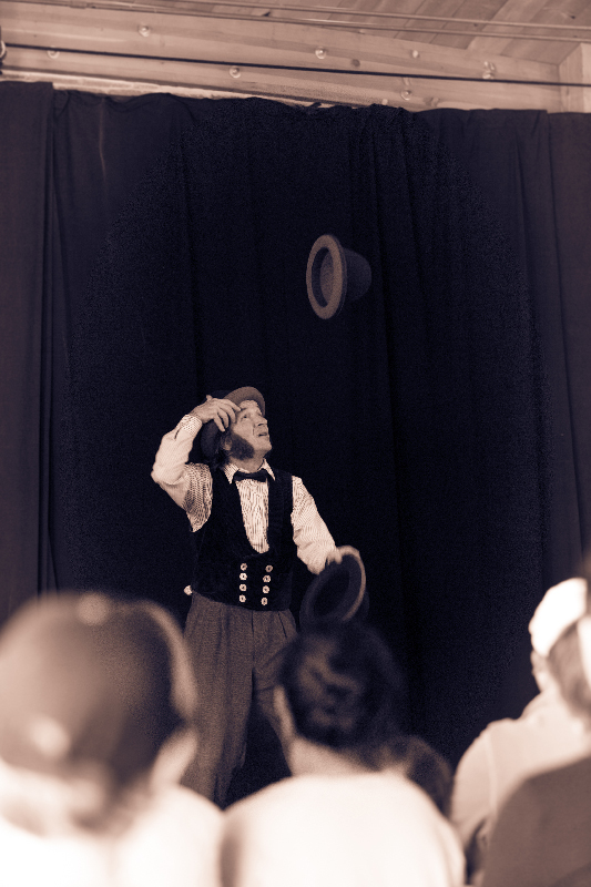 black and white photo of Slim juggling hats for an audience