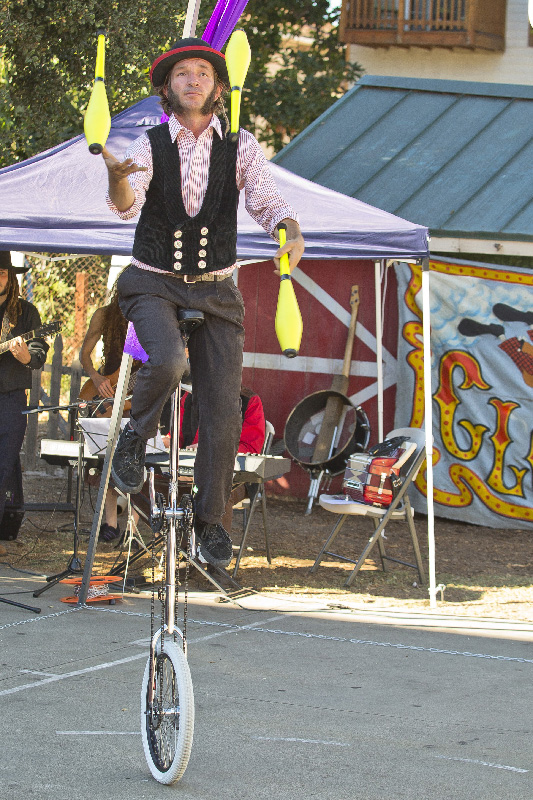 Slim juggling pins while unicycling outdoors